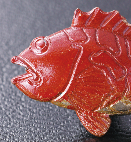  カサゴの赤は煮色という技法で生まれます。エビフライの黄金は、緊迫を施し、フグは、金銀メッキと硫化の技法が使われています。