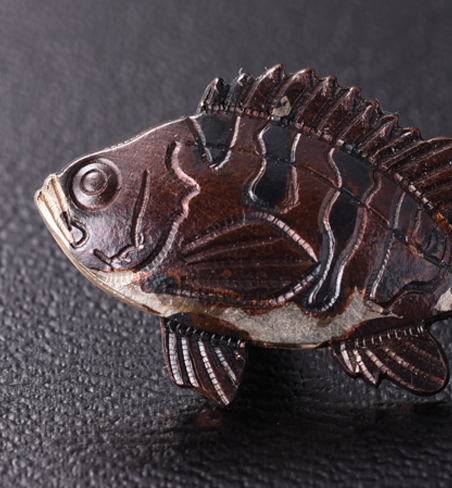  カサゴの赤は煮色という技法で生まれます。エビフライの黄金は、緊迫を施し、フグは、金銀メッキと硫化の技法が使われています。